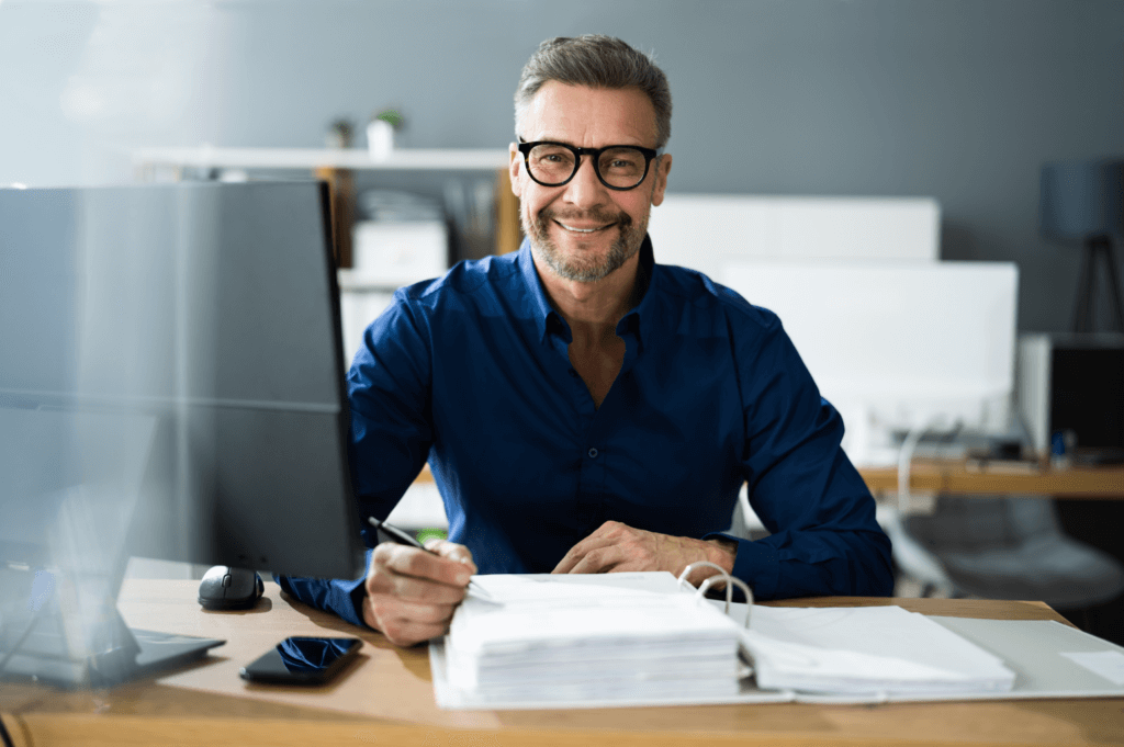 Man sitting in front of computer and writing on a page in a 3-ring binder