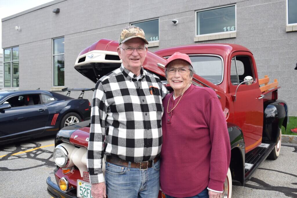 A couple pose in front of their classic car