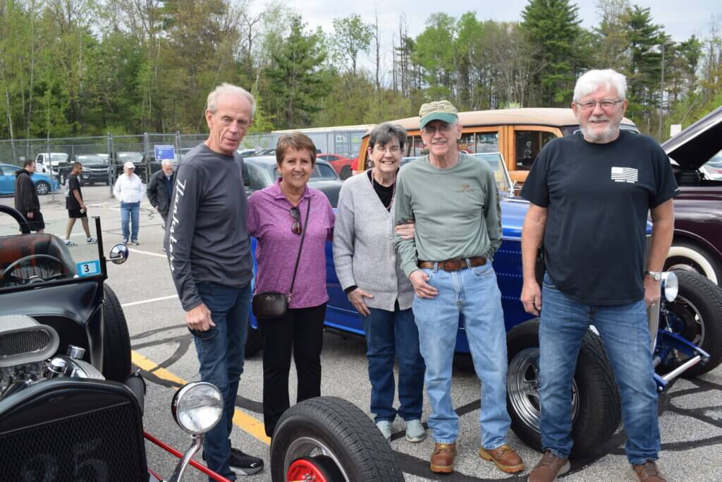 Group stands in front of a row of classic cars