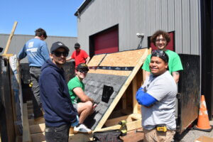 Students standing near the mock-up of a roof for a weatherization training