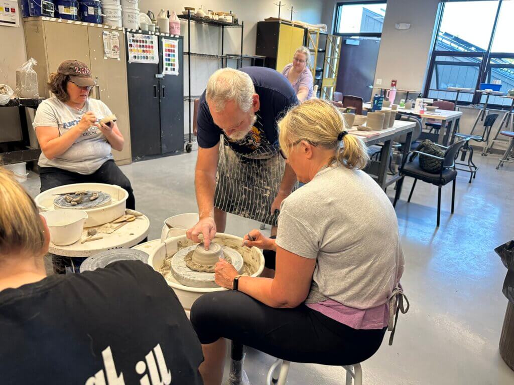 Instructor working with pottery students